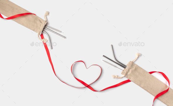 Ecological stainless steel straws in a linen caseand red heart ribbon on a white background