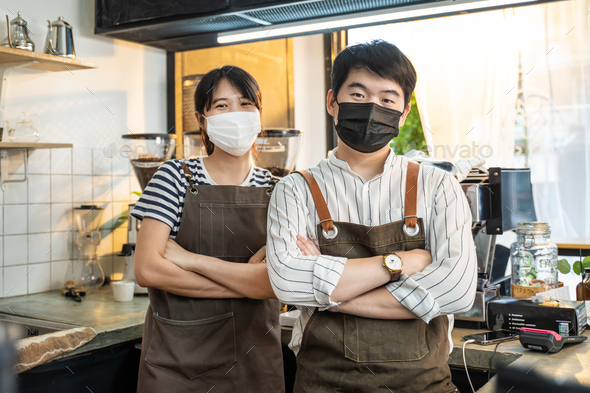 Portrait of attractive Asian waiter and waitress at restaurant cafe.