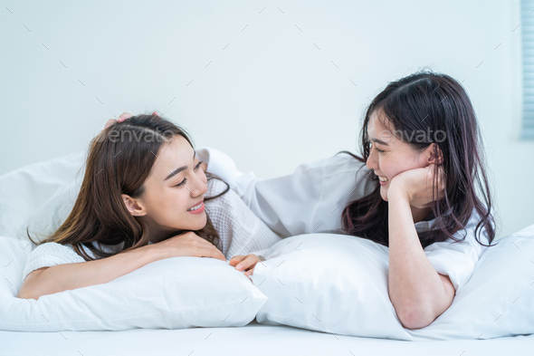 Asian beautiful lesbian couple wake up from sleep in bedroom in morning.
