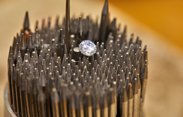 Jewelry production. The diamond is held with tweezers against the background