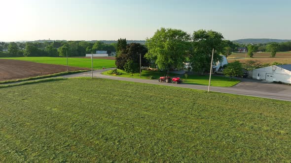 Aerial approach towards red tractor with baler attached. Beautiful spring day in Amish country. alt