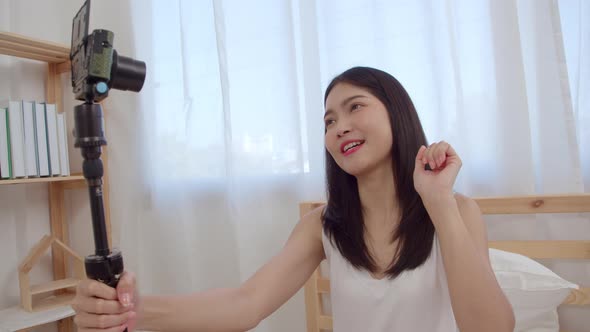 Young Asian woman vlog at home using camera making vlog video to social media in bedroom. alt