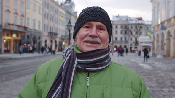 Portrait of Old Senior Man Tourist Smiling Looking at Camera in Winter City Center of Lviv Ukraine alt