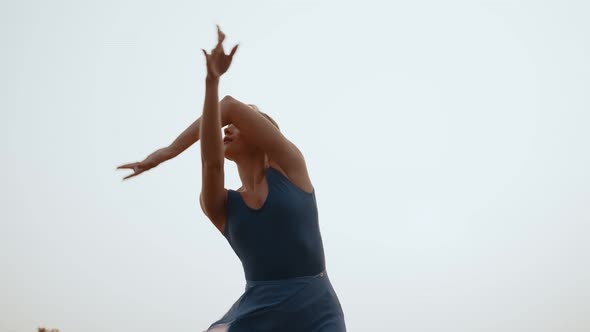 Woman Performs Ballet Movements with Her Hands Background Sky Bottom View alt