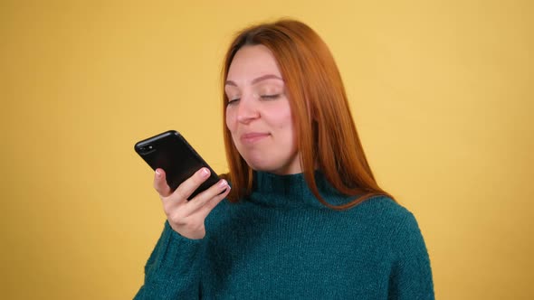Close Up Young Woman Recording Voice Message and Happily Looking in Camera Over Colorful Background