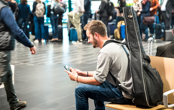 Hipster man at international airport using mobile smart phone