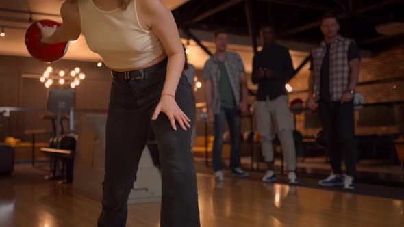 Portrait of a Young Woman Throwing a Bowling Ball and Knocking Out a Shooter Who Jumps and Dances alt