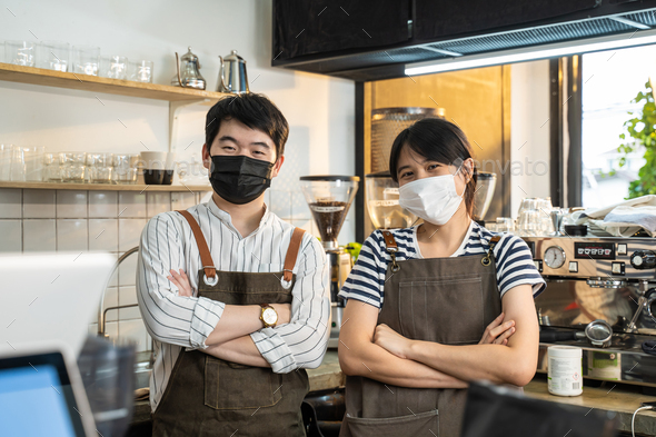 Portrait of attractive Asian waiter and waitress at restaurant cafe.