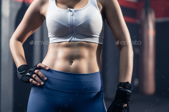 Close up of unrecognized young athlete Asian girl in sportswear standing  with six packs abs in gym Stock Photo by s_kawee