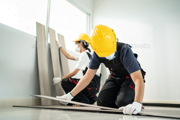 Construction worker installs laminate board on floor to renovate house due to Covid-19