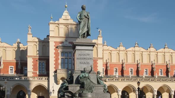 Statue of Adam Mickiewicz and Sukiennice Buidning in Cracow Poland alt