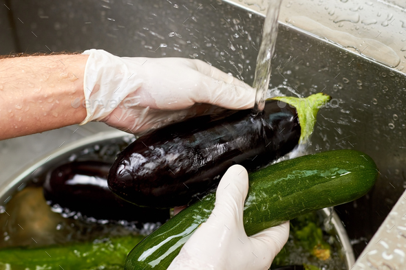 Black eggplant rinsing by stream of tap water.
