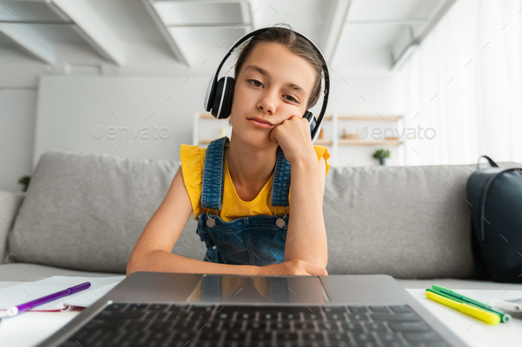 lazy teenager boy play computer games, sit in headphones, looking at screen  of laptop, free time at home Stock Photo
