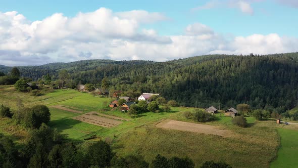 Birds eye view of little settlement among beautiful nature, mountains, and forests alt