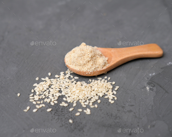 sesame flour and sesame seeds in a wooden spoon. alternative type of flour. gluten free product