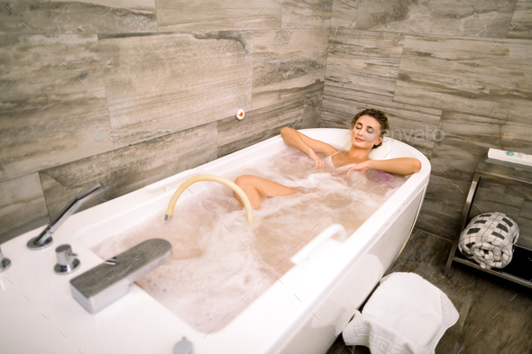 Healthy Spa. Young Caucasian Beautiful Relaxing Woman Lying in the Bath with Hydro Massage