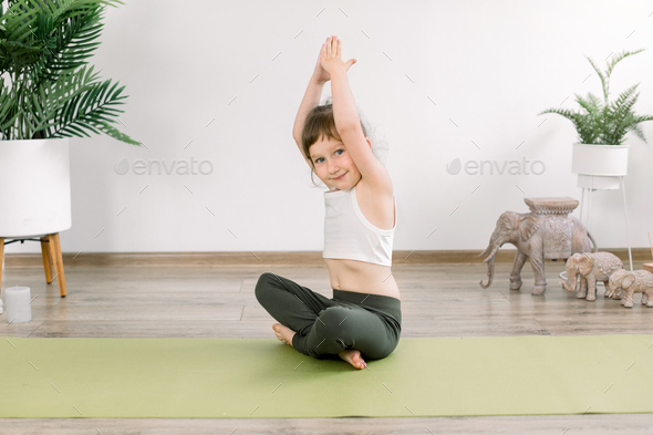Healthy child girl, doing exercise in sportive top and leggings, practicing yoga