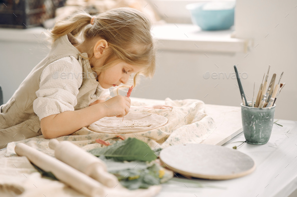 Little girl makes a clay plate and decorates it