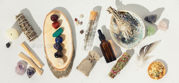 Healing crystals, elixir, palo santo, white sage bundle on abalone sea shell, dry healing herbs