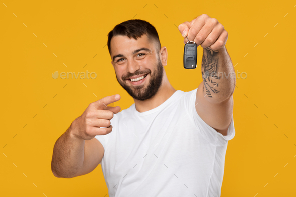 Happy smiling mature handsome european guy in white t-shirt show finger at keys of new car