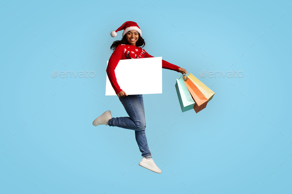 Happy black lady with empty board shopping while xmas sales