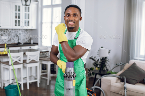 Smiling afro american man posing with vacuum cleaner