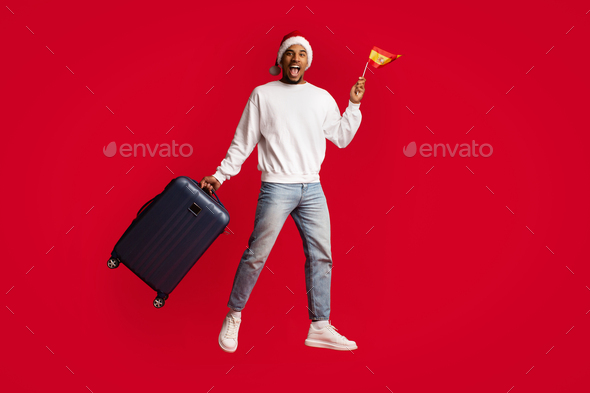 Cheerful black guy holding flag of Spain and suitcase