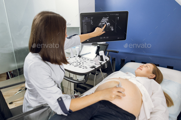 Back view of female ultrasound technician, scanning pregnant woman\'s belly