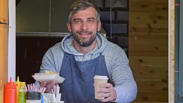 joyous shop assistant holding out street food