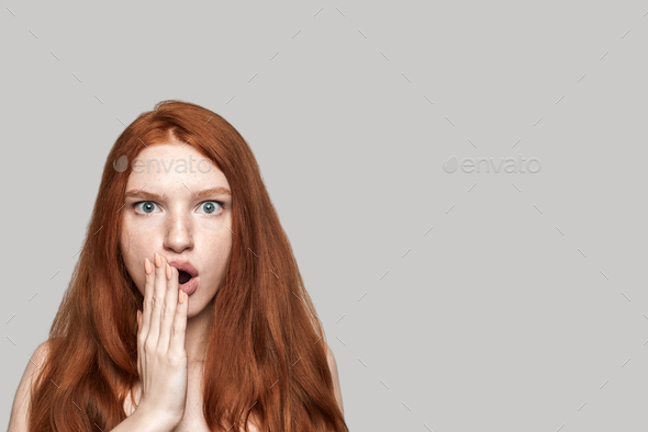 I don\'t believe Studio shot of cute redhead surprised girl making shocked face while standing