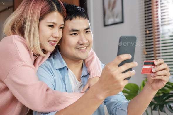 Asian couple use mobile phone shopping online with credit card together