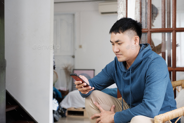 asian man using mobile surfing internet and social media at home