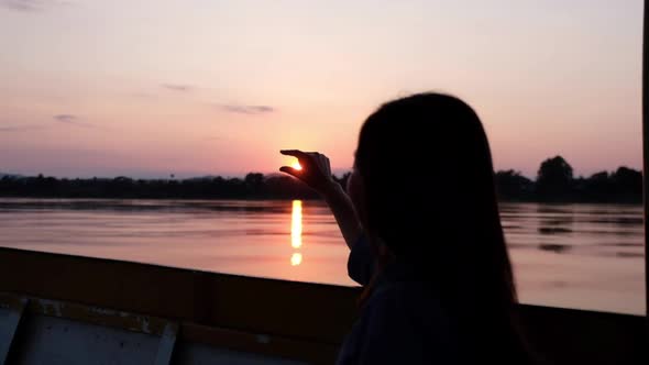 Slow motion of a female traveler playing and touching the sun while sailing a long tail boa