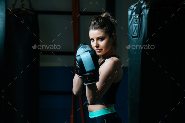 Sportswoman in boxing gloves in gym