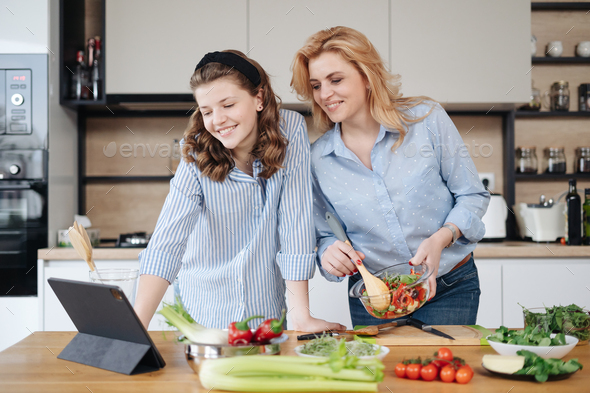 Mother and daughter teenager cooking together Stock Photo by diignat