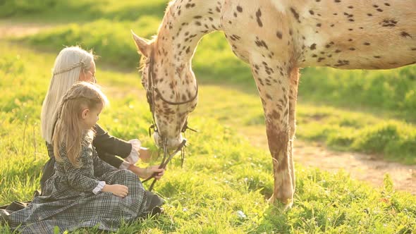 Mother and Daughter Feed a Horse