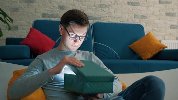 Magic Concept  Portrait of Surprised Young Man Opening Gift Box alt