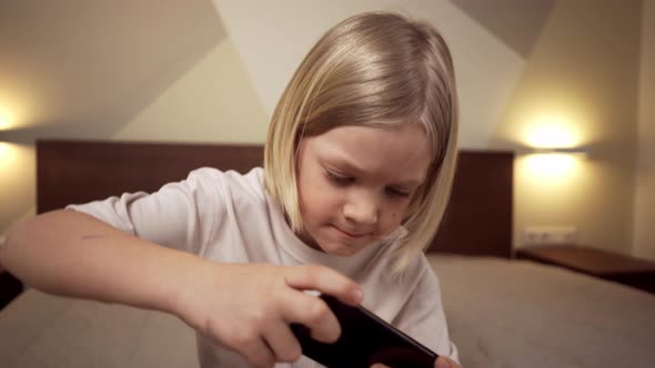 Cute Blonde Boy Cheerful Kid Playing Games On The Phone