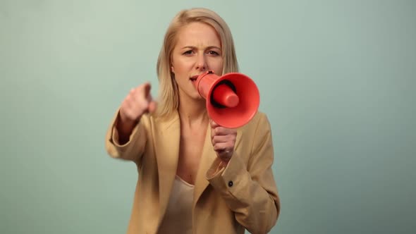 Beautiful woman in jacket with megaphone on blue background alt