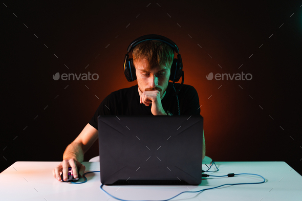 Gamer playing video games with headphones on neon light background