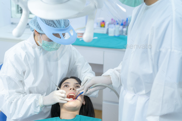 Asian expert dentist doctor wear PPE and mask examine patient's teeth at dental clinic.