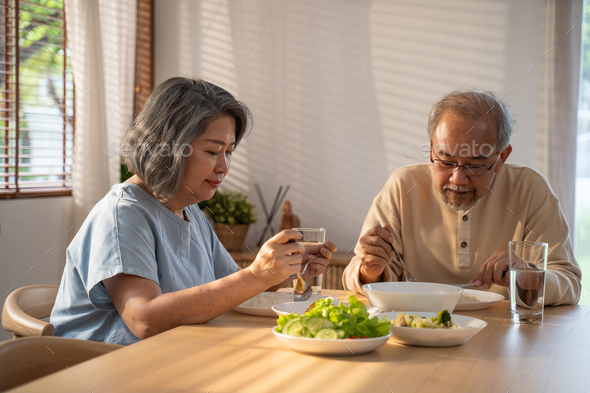 Asian Senior olderly couple people eat food on dinner table in morning together at home.