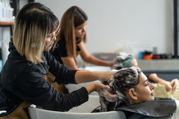 Asian expert Hairdresser massaging and washing hair of young customers.