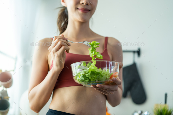 Close up of Asian sport girl in sportswear enjoy eat clean vegetables after exercise for health