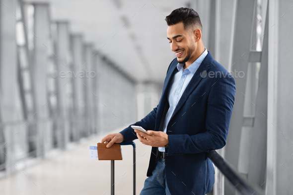 Booking Hotel Online. Young Arab Businessman Using Smartphone While Waiting In Airport