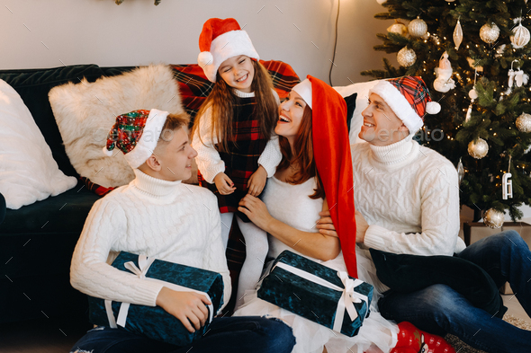 Close-up portrait of a happy family sitting on a sofa near a Christmas ...