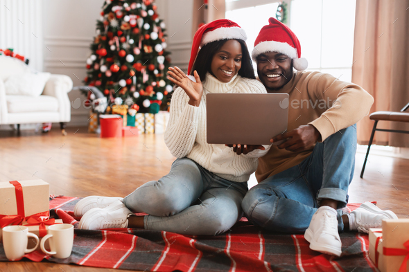 Black family using pc making videocall on Xmas waving hands