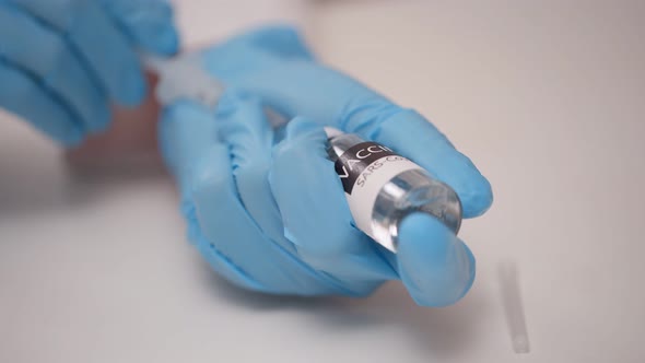 Close Up of Doctor Hands in Blue Protecting Gloves Fills the Vaccine From the Vial Into the Syringe