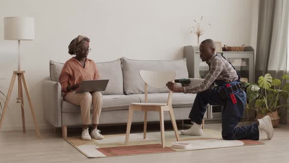 Skillful Joiner Assembling Furniture for African Woman alt