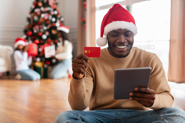 Xmas Online Shopping. Smiling guy using tab showing credit card